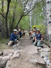 An image of a group of workers are crouched down on either side of a trail. 